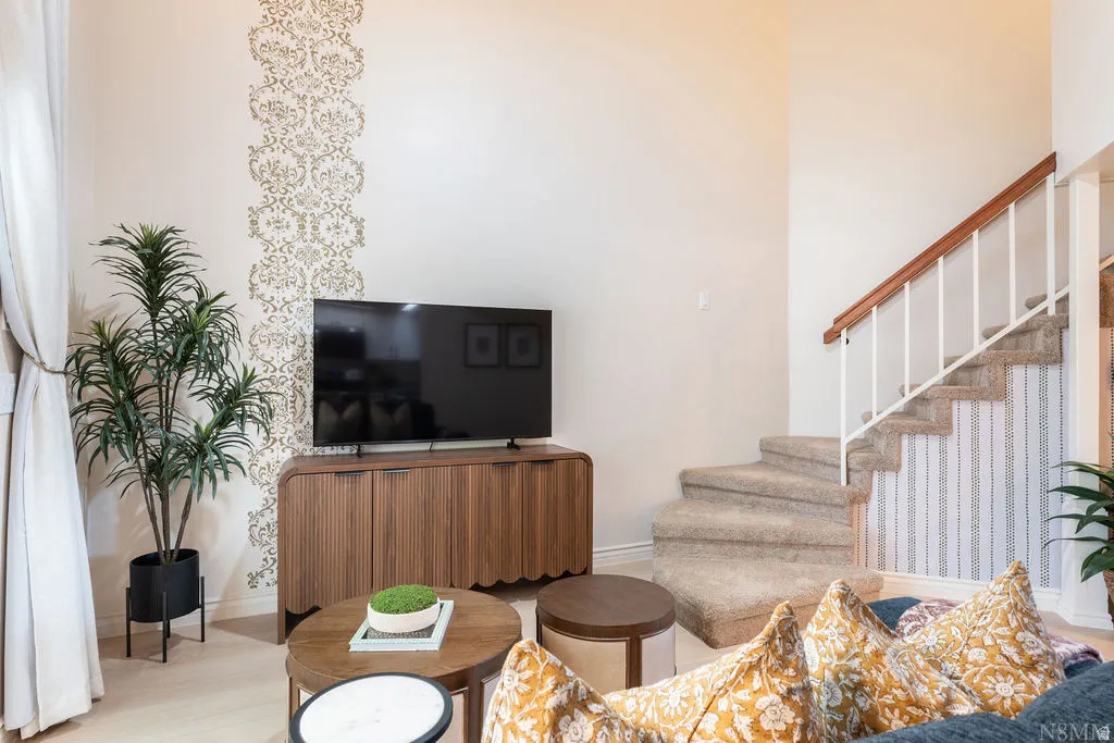 Carpeted staircase with wooden handrail, white balusters, and a decorative wallpaper accent