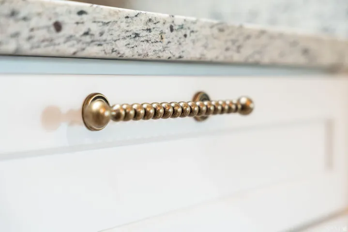 White cabinetry with bronze-finish hardware and a speckled countertop