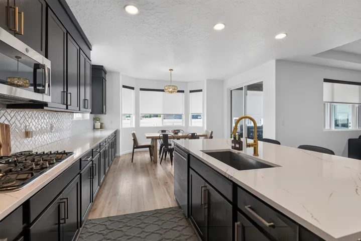 Kitchen featuring dark cabinetry, light countertops, a herringbone tile backsplash, and wood-finish flooring