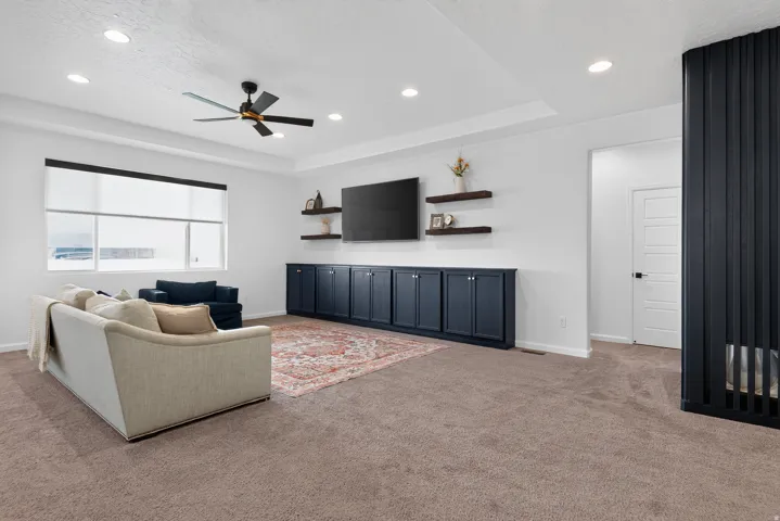Recessed lighting, tray ceiling, ceiling fan, expansive window, and extensive built-in cabinetry