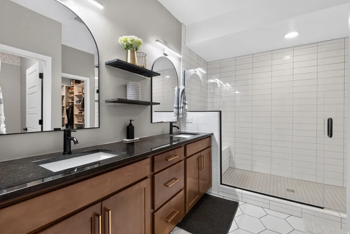 Double vanity with dark countertops and wood-finish cabinetry