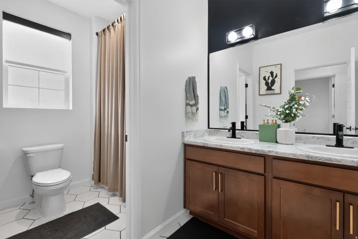 Dual vanity with wood-finish cabinetry, white countertop, and matte black fixtures