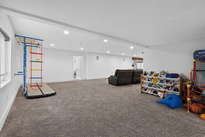 Expansive carpeted area with recessed lighting and a white interior door