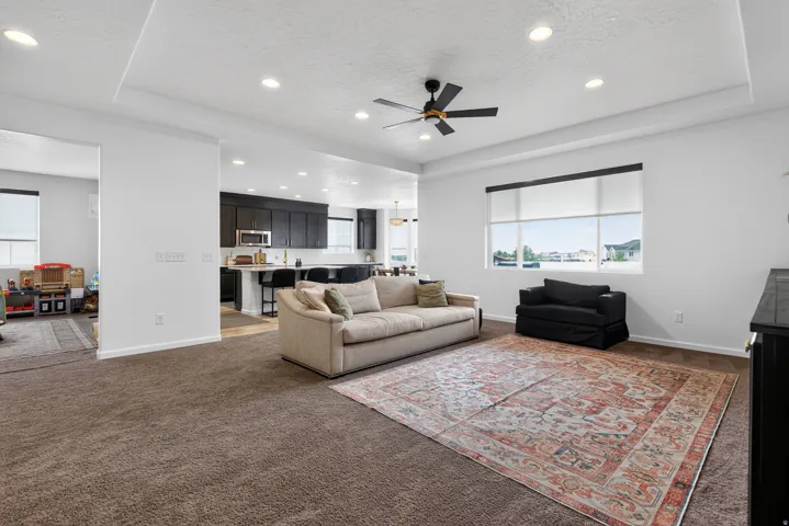 Spacious living area featuring tray ceiling, recessed lighting, and large windows
