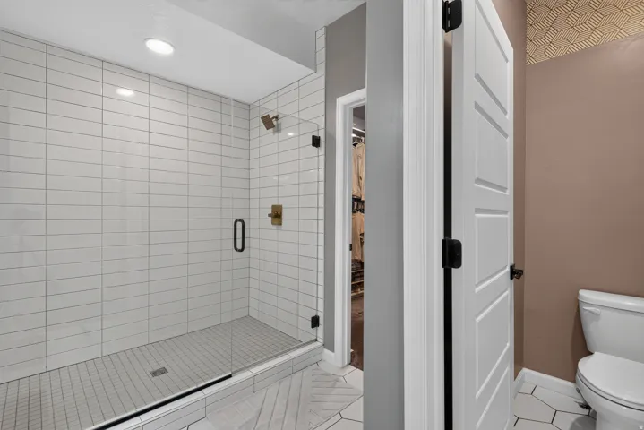 Walk-in shower with horizontal subway tile, glass enclosure, and gold-finish fixtures
