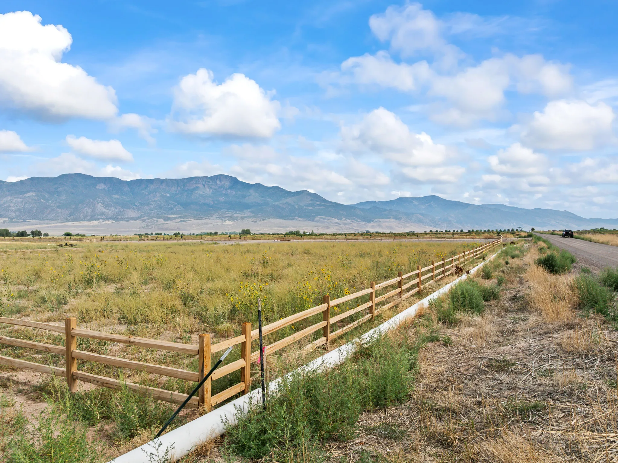 Expansive open fields with a rustic wood fence and distant mountain range