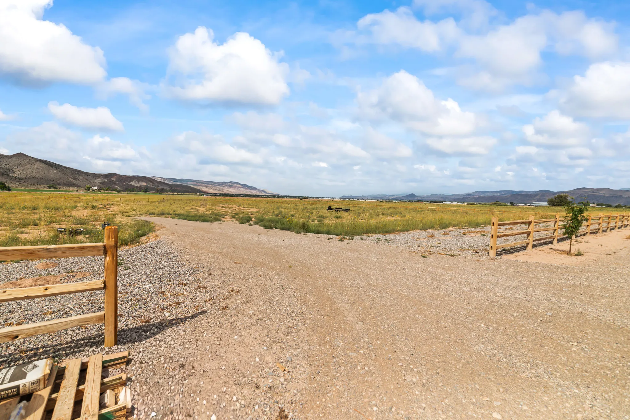 Expansive land parcel featuring natural ground cover, mountain backdrop, and split rail fencing