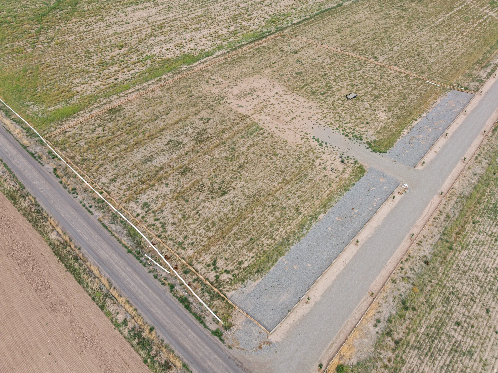 Expansive land parcel featuring a paved road, gravel driveways, and delineated property lines