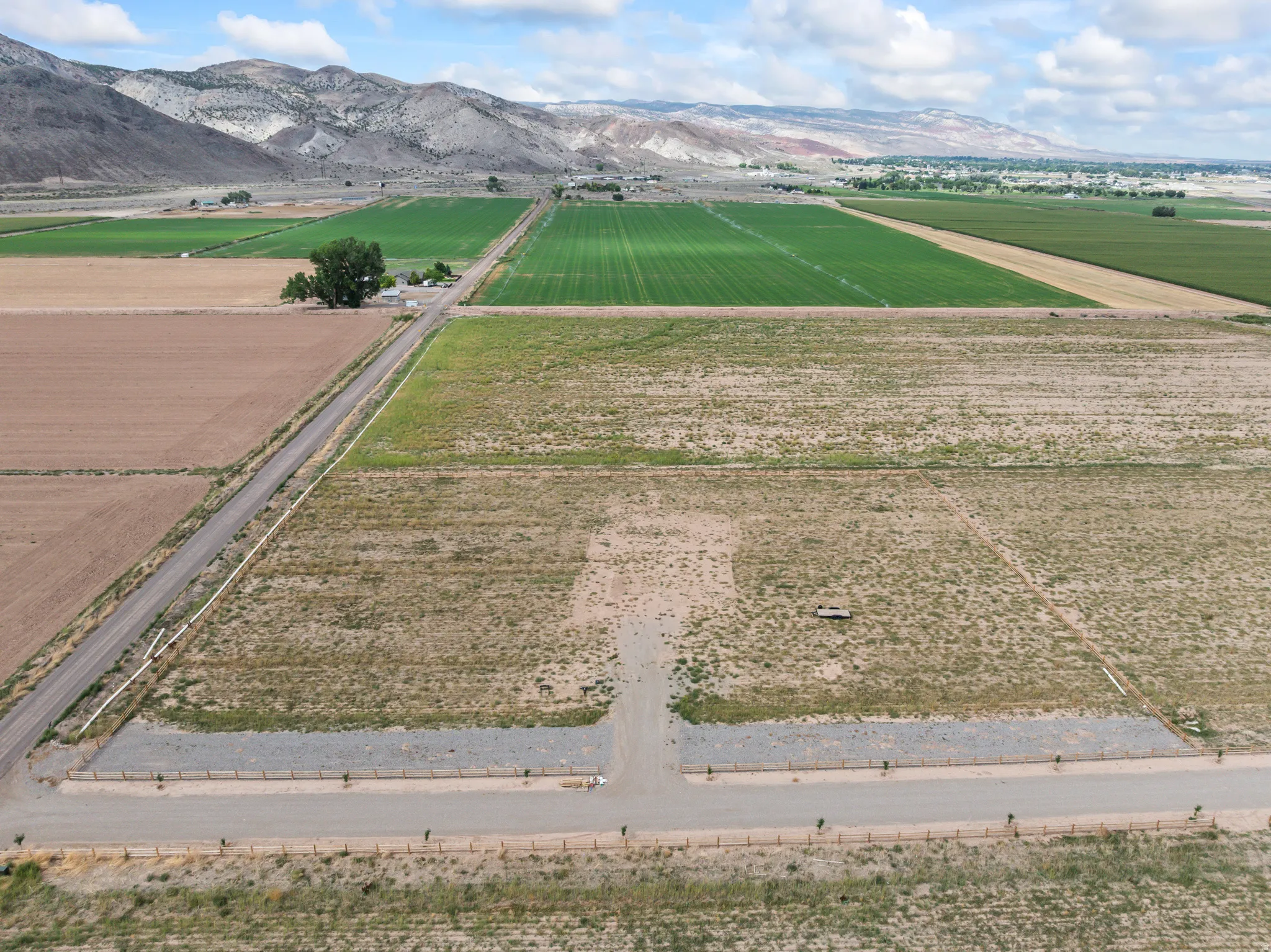 Expansive open land with a gravel road, gravel driveway, and partial fencing