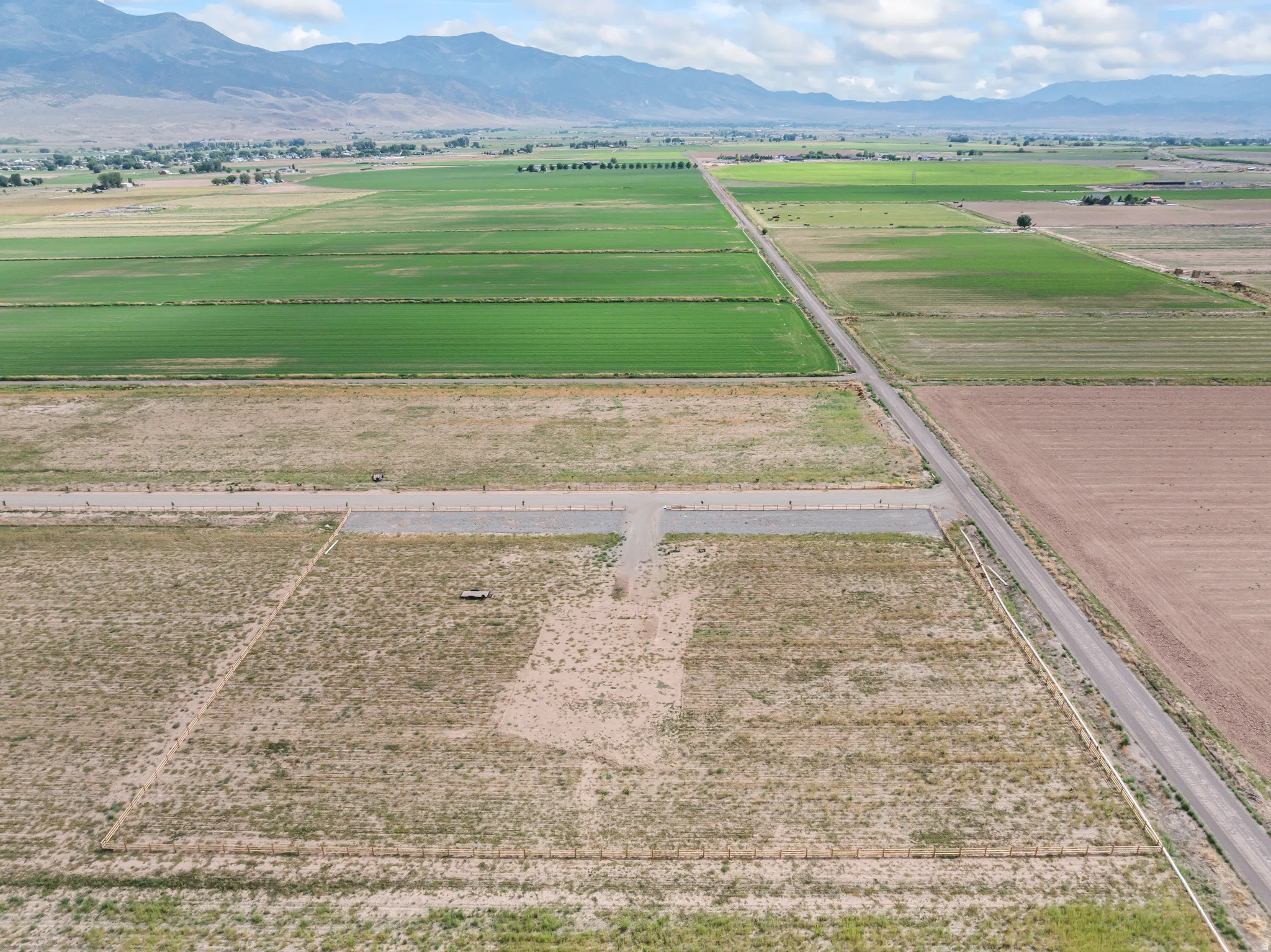 Expansive parcel featuring a graded access area, surrounded by agricultural land, with distant mountain ranges