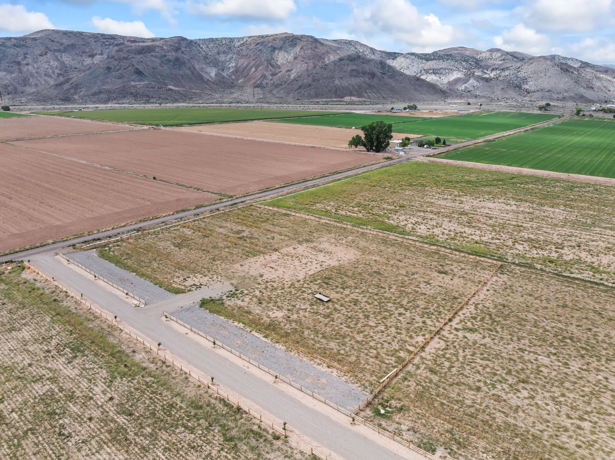 Expansive land parcels featuring established access roads, a distinct fence line, and a mountainous backdrop