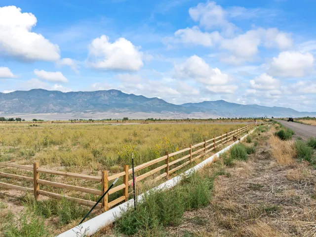 Expansive open fields with a rustic wood fence and distant mountain range