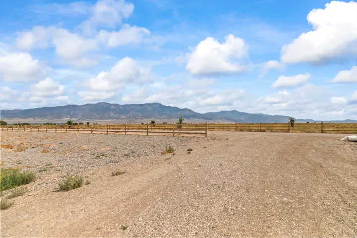 Expansive open land with a wooden post and rail fence, featuring a distant mountain range