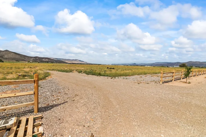 Expansive land parcel featuring natural ground cover, mountain backdrop, and split rail fencing