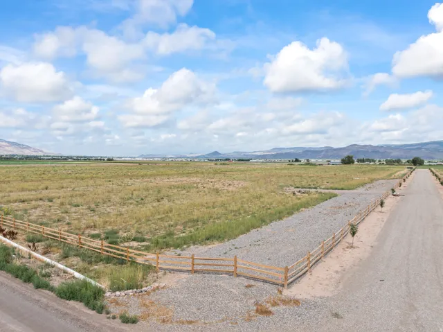 Expansive land parcel featuring natural ground cover, mountain backdrops, and a split-rail fence boundary