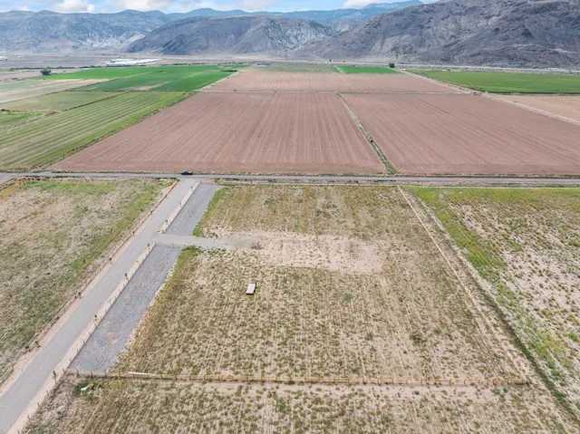 Expansive land parcel with graded access road, perimeter fencing, and mountain backdrop