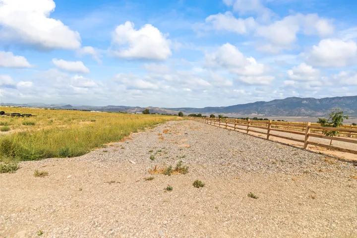 Expansive land parcel featuring a gravel-surfaced path, natural vegetation, and a rustic wooden fence