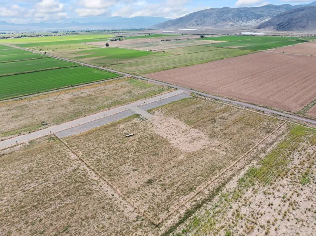 Expansive land parcel featuring partial fencing, gravel access roads, and distant mountain scenery