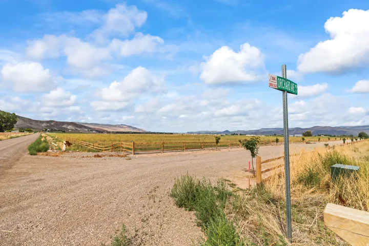 Gravel road access with a wooden fence line bordering open fields