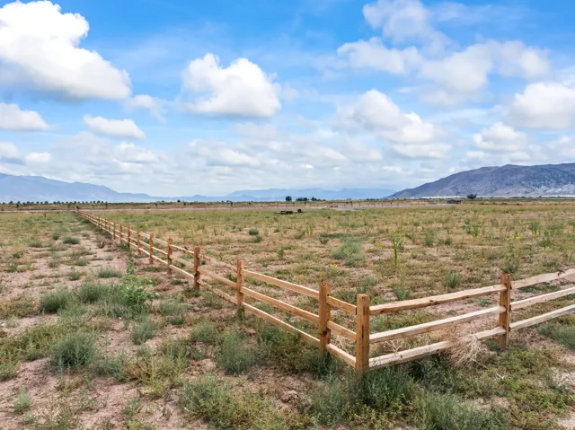 Expansive acreage featuring a natural wood split-rail fence, open terrain, and distant mountain backdrops