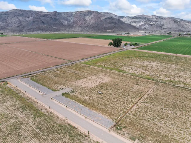 Expansive land parcels featuring established access roads, a distinct fence line, and a mountainous backdrop