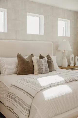 Upholstered headboard with an integrated bed frame, light-toned wall covering, and transom windows