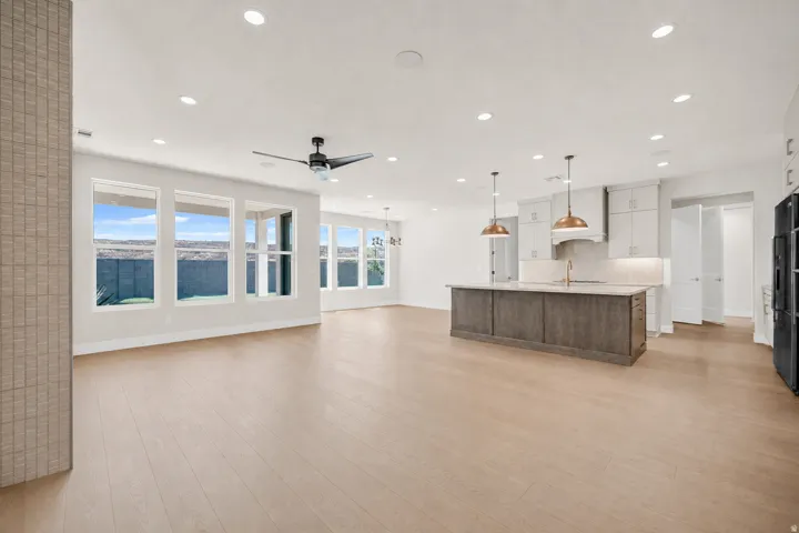 Open-concept living area with wood-finish flooring, a contemporary kitchen island, recessed lighting, and expansive windows