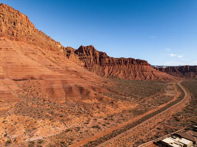 Expansive desert landscape featuring rugged red rock formations, natural terrain, and a clear sky backdrop