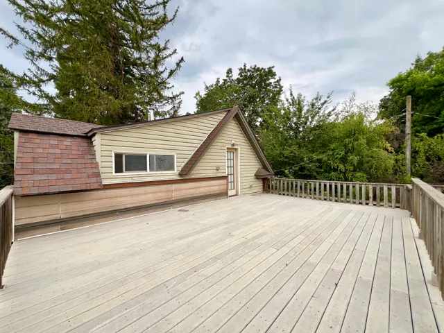 Expansive outdoor deck with wood railing, featuring an exterior door and horizontal windows