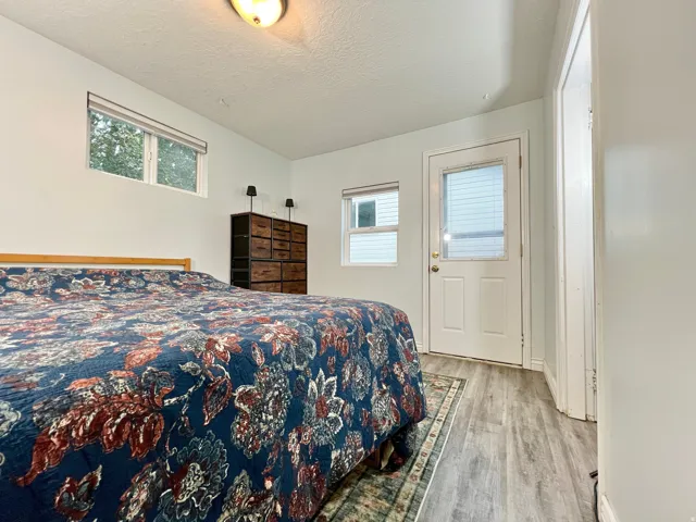 Light-colored walls with wood-finish flooring, featuring a window with a roller shade and a white door with a window