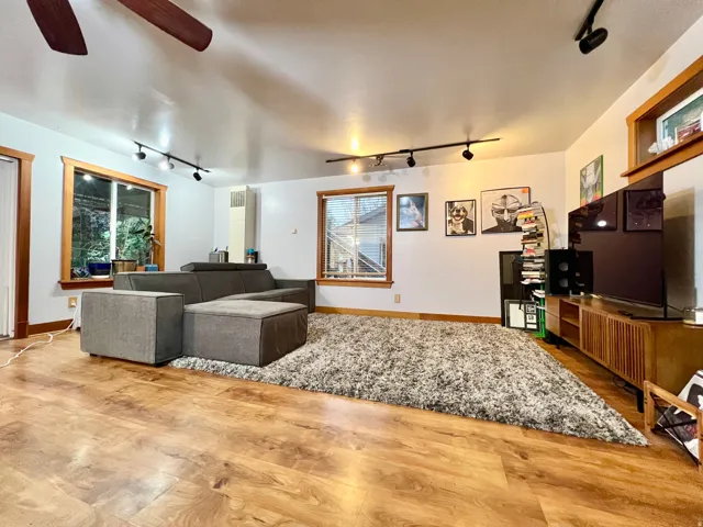 Wood-finish flooring, white walls, and a ceiling fan with integrated lighting