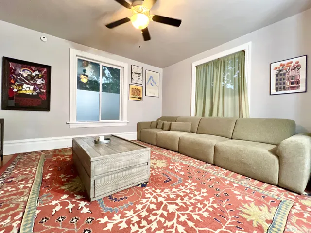 Hardwood flooring, painted walls, ceiling fan with light fixture, and window with trim