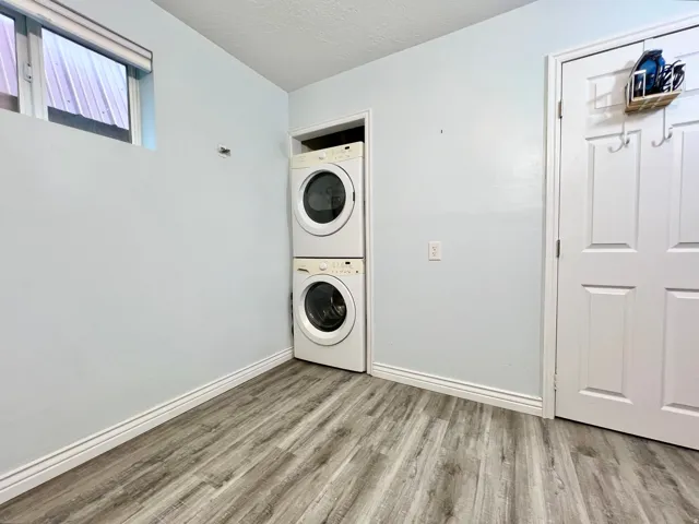 Wood-finish flooring, white paneled door, window with blinds, and white baseboards