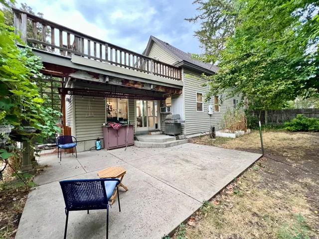 Spacious concrete patio with direct outdoor access and an upper-level wooden deck
