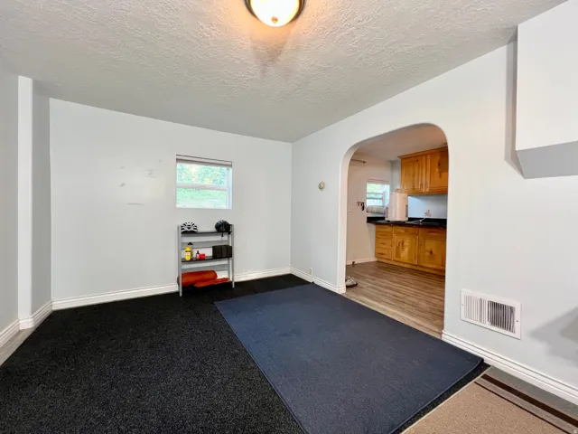 Archway entry to kitchen, featuring wood-finish flooring, wood cabinetry, and dark countertops