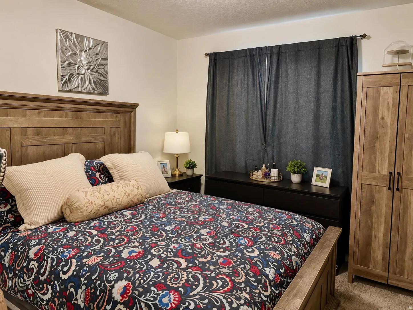 Wood-finish bed frame, dark fabric window coverings, built-in dresser, and a wood-finish wardrobe