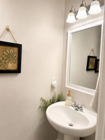 Pedestal sink with chrome fixtures and a framed mirror