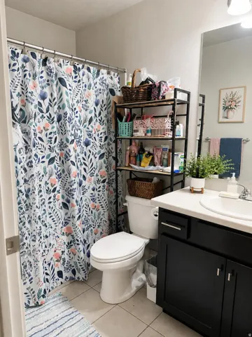 Bathroom featuring a single vanity with dark cabinetry, integrated sink, and a framed mirror
