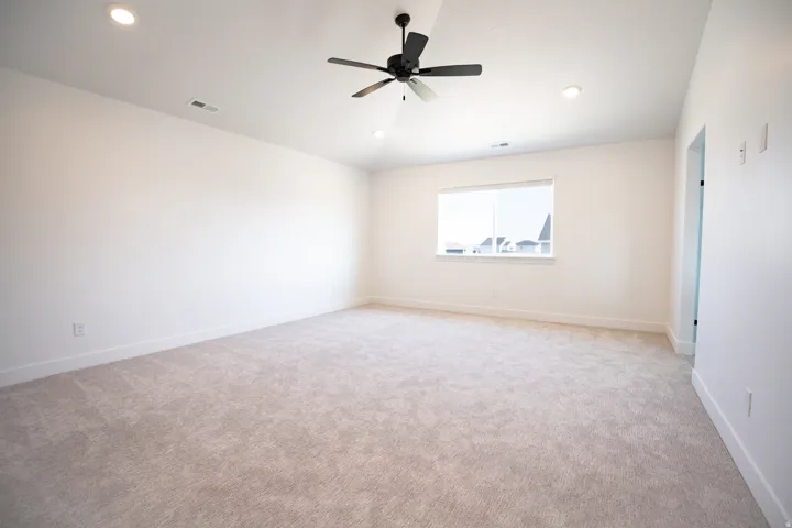 Huge primary bedroom with vaulted ceilings and a ceiling fan