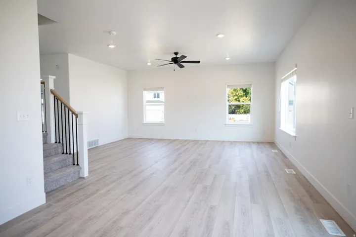 Spacious family room with wood laminate flooring and a ceiling fan