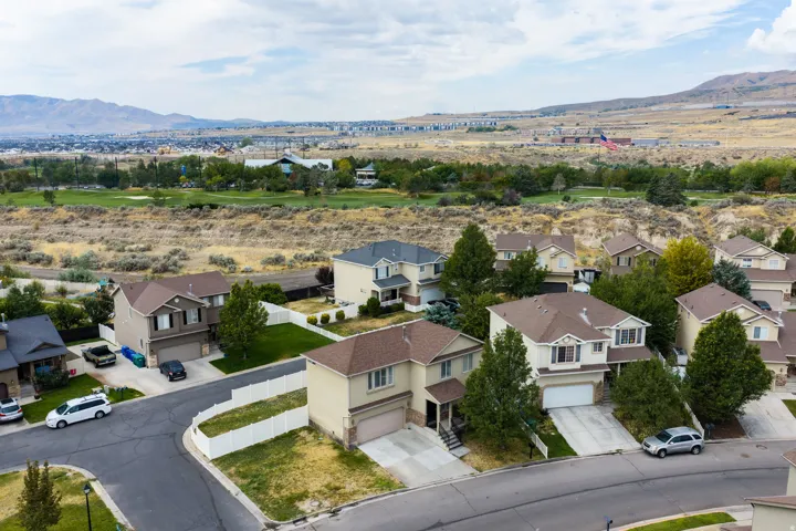 Residential street with established homes, mature trees, and a mountain backdrop