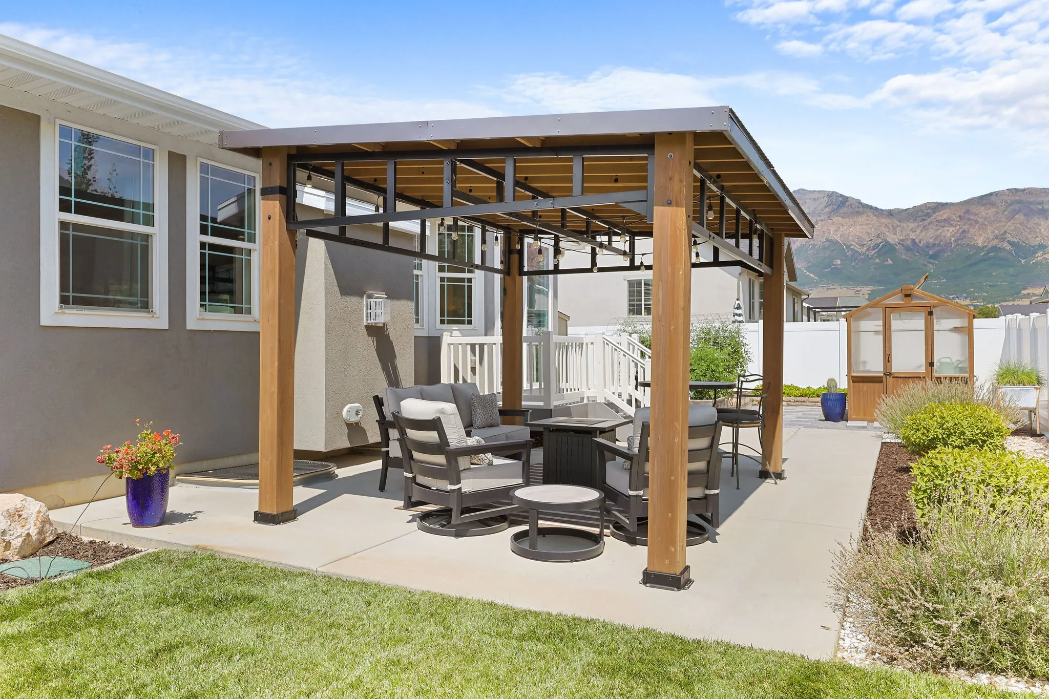 Backyard featuring a covered patio, concrete hardscaping, manicured lawn, and mountain scenery
