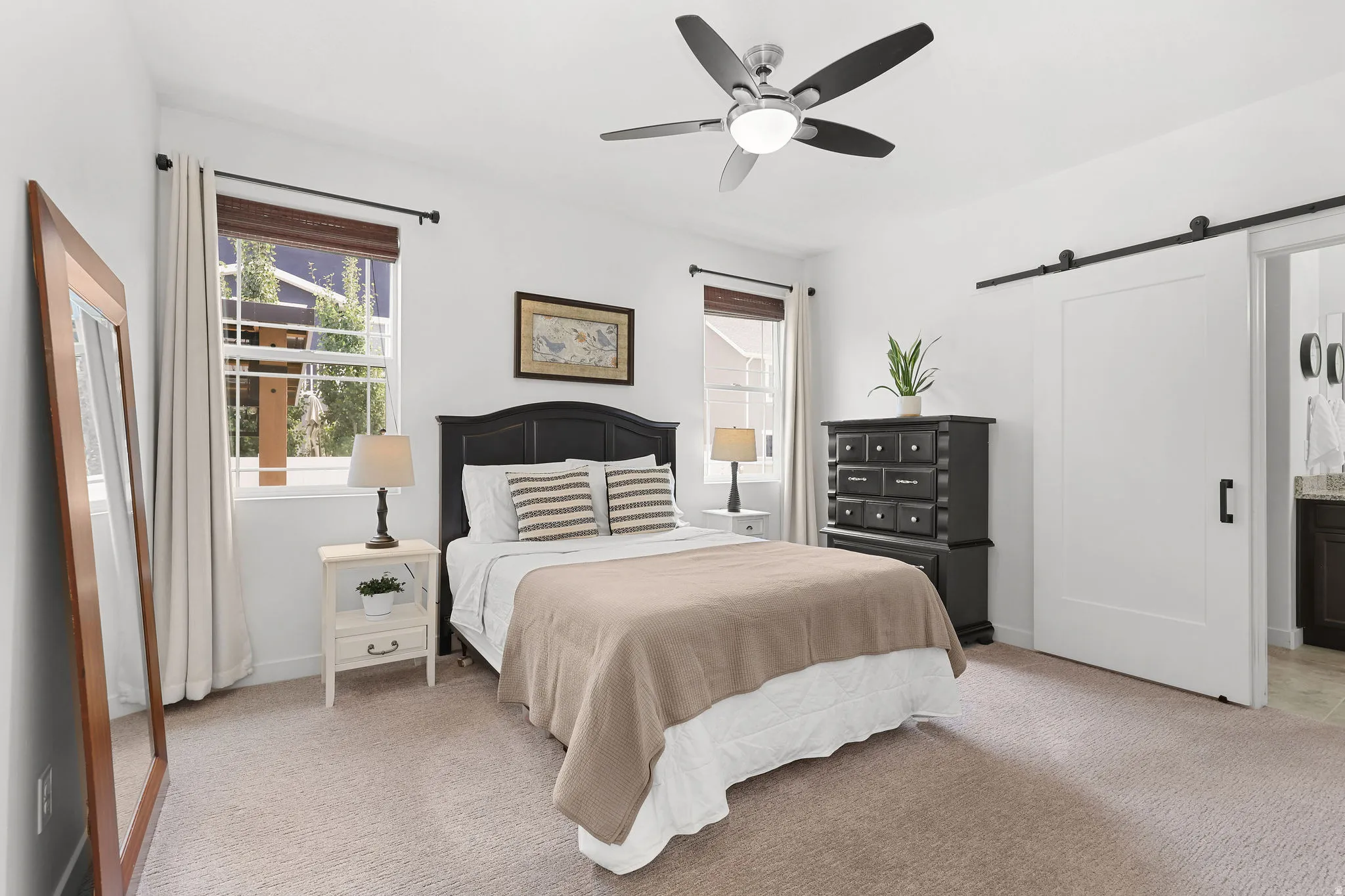 Neutral-toned carpeting paired with white walls, featuring a ceiling fan with integrated lighting