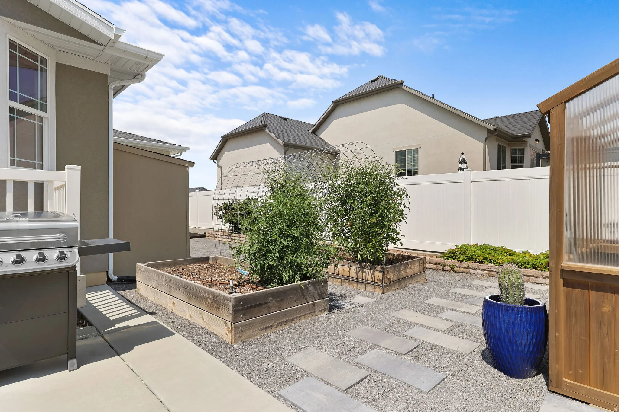 Landscaped outdoor area featuring gravel, rectangular stepping stones, and raised garden beds