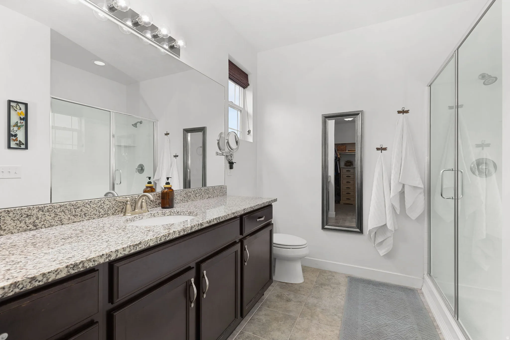 Double vanity with a granite countertop, undermount sinks, and dark wood cabinetry