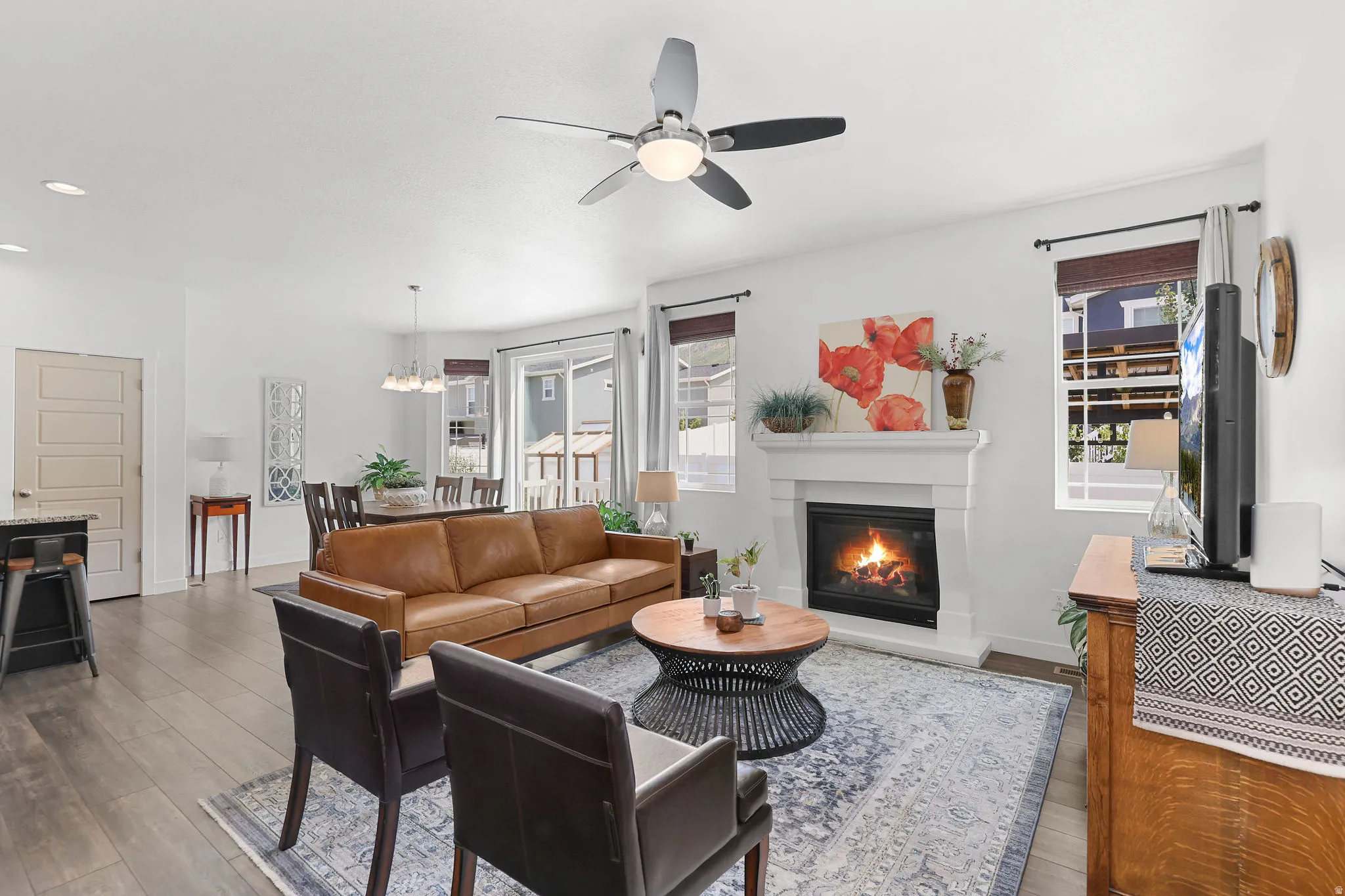 Open-concept living area featuring wood-finish flooring, a white mantel fireplace, and recessed lighting