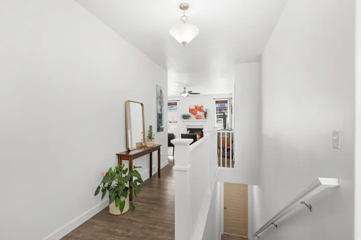 Wood-finish flooring, white painted walls, white spindle staircase, and an overhead flush-mount light fixture