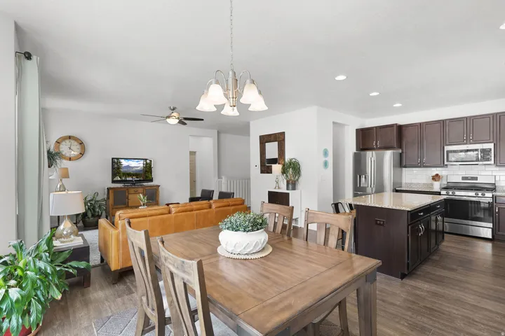 Open-concept living space featuring wood-finish flooring, recessed lighting, a ceiling fan, and a kitchen with stainless steel appliances, dark wood cabinetry, and a light-toned countertop
