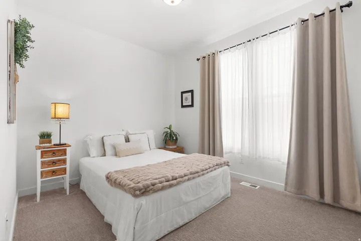 Plush carpeting, a large window with sheer and blackout drapery, and a ceiling-mounted light fixture