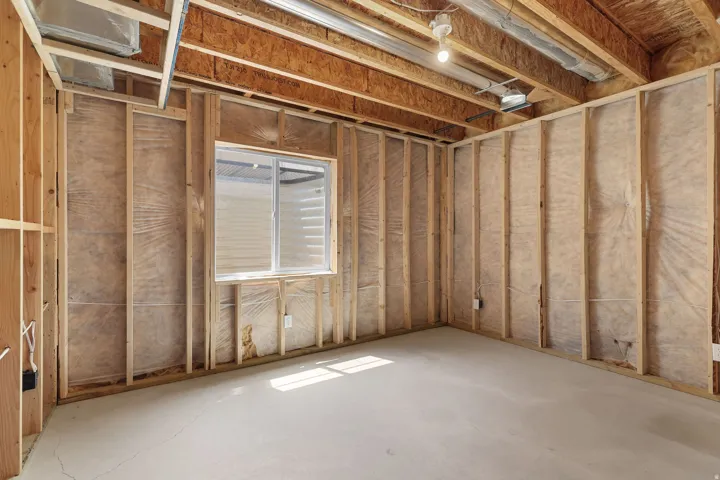 Unfinished lower level with wood framing, exposed ceiling joists, and a basement window